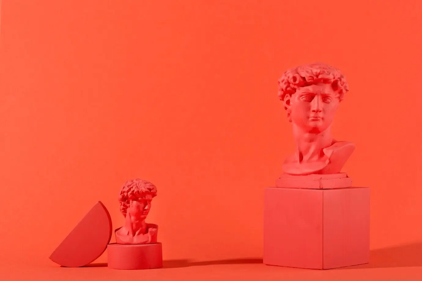 Гипсовый бюст на коралловом фоне с геометрическими фигурами.